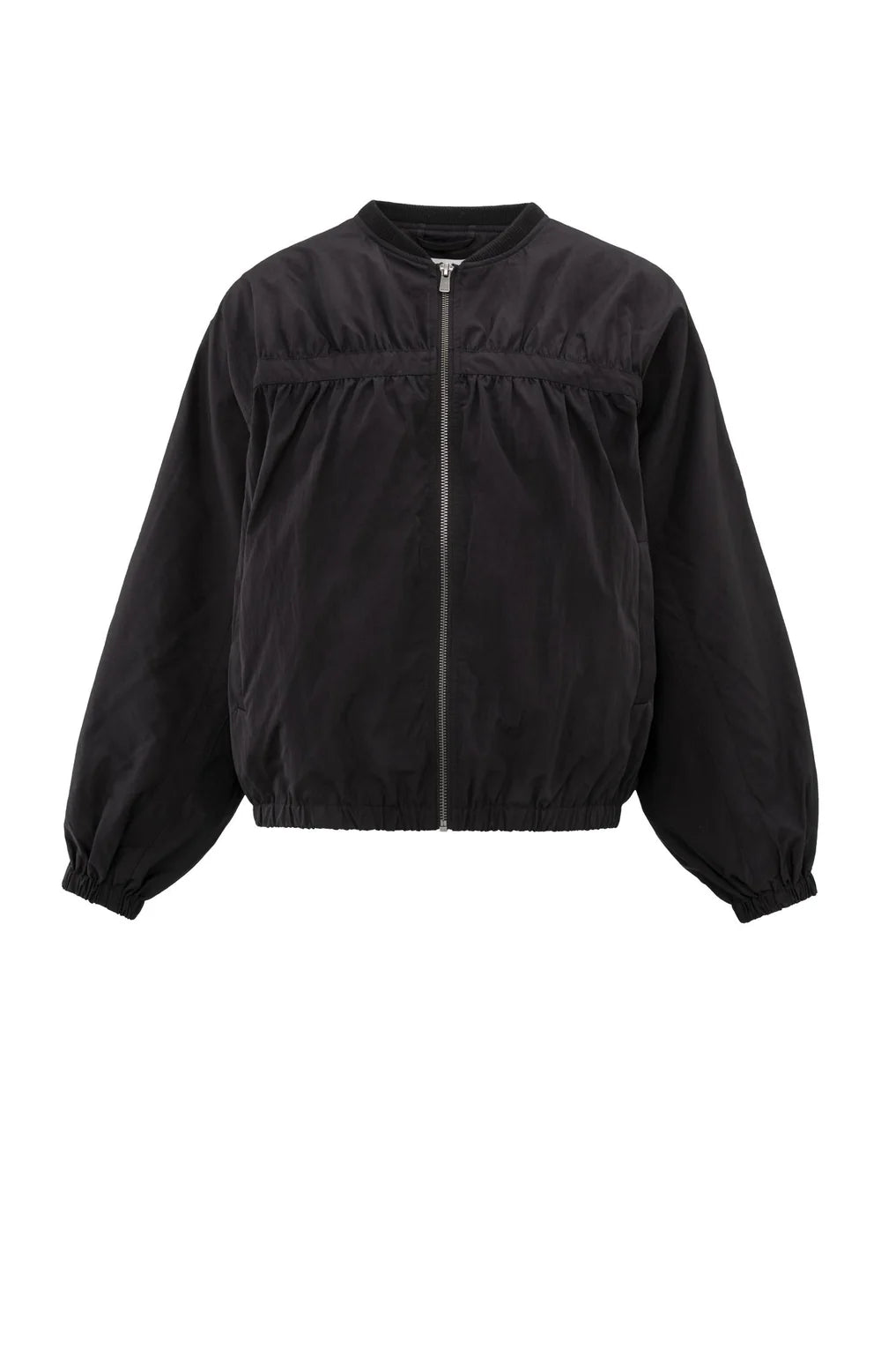 A women's lightweight bomber jacket in a soft beige color with a relaxed, slightly oversized fit. It features a round neckline, a full-length front zipper, and gathered detailing along the chest for a subtle textured effect. The long sleeves are voluminous and taper into elasticated cuffs, while the hem also has an elastic finish for a comfortable and slightly cropped silhouette.